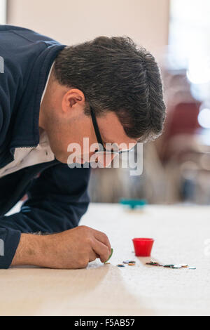 Cambridge, Regno Unito. Il 31 ottobre, 2015. Un concorrente ritiene la sua prossima mossa. L'inglese Tiddlywinks coppie nazionali si svolgono campionati a Selwyn College di Cambridge Regno Unito. Lungi dall essere un gioco da bambini, la concorrenza è un mix di strategia e destrezza per la propulsione della "winks" utilizzando un "squidger" in una pentola o per coprire gli avversari "winks". La nascita del moderno gioco può essere ricondotto a un gruppo di Cambridge (UK) laureandi in 1955. Credito: Julian Eales/ Alamy Live News Foto Stock