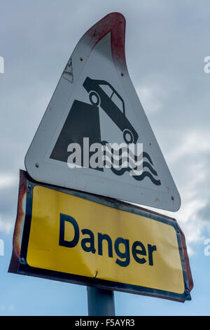 Cartello di avvertenza accanto al parcheggio vicino al fiume. Metafora per i pericoli di una Brexit dura, di un concetto di caduta, di una valutazione della sicurezza, di Oops. Cartelli stradali Regno Unito. Foto Stock