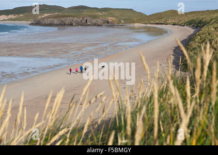 La famiglia e il cane a camminare lungo la riva della spiaggia di sabbia dune di sabbia Scotlands costa nord Foto Stock