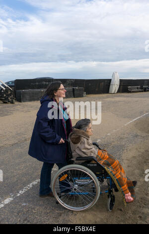 A 95 anno vecchia donna fuori con il suo accompagnatore o assistente sul pontile a Broadstairs, ben confezionato contro il freddo in una luminosa giornata autunnale. Foto Stock