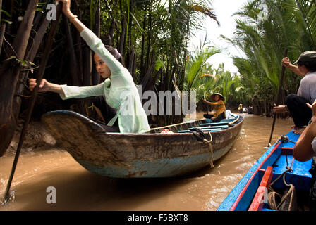 Donna su una barca a remi sul fiume Mekong, vicino a My Tho village, Vietnam. Bao Dinh canale, delta del Mekong. La donna a non conica hat Foto Stock