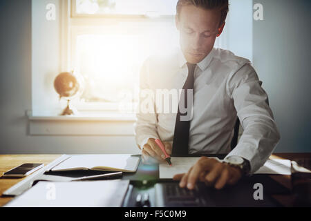 Executive business uomo al lavoro su conti pur essendo concentrato e serio, indossa una camicia bianca e cravatta Foto Stock