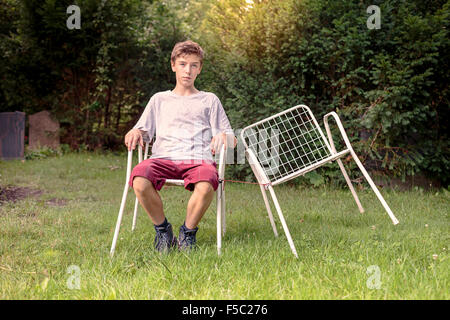 Lonely ragazzo adolescente con due sedie Foto Stock