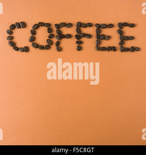 Caffè sillabato con chicchi di caffè tostati, su sfondo arancione Foto Stock