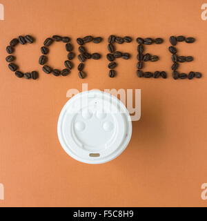 Caffè sillabato con chicchi di caffè tostati, su sfondo arancione Foto Stock