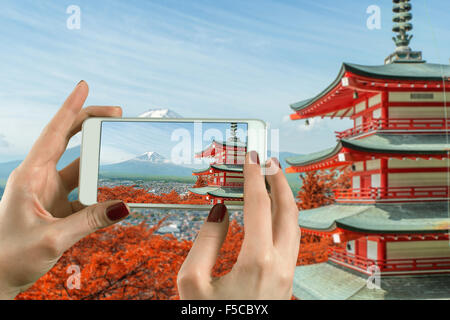 Vista posteriore di una donna prendendo fotografia con uno smart phone fotocamera a Mt. Fuji con i colori dell'Autunno in Giappone. Foto Stock