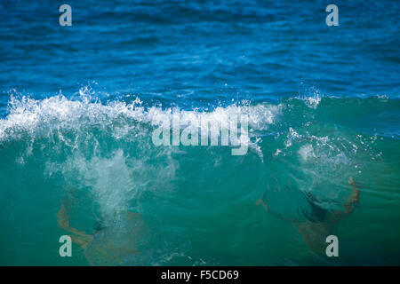 Oceano retroilluminato di onde che si infrangono sulle rive del Gran Canaria, due bagnanti indistintamente visto attraverso l'acqua Foto Stock