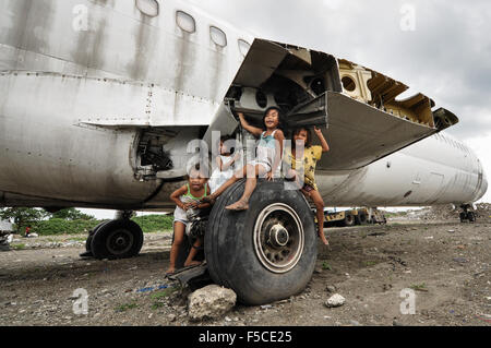 I bambini giocano sul relitto di un aereo in un lotto vacante in Paranaque City, a sud di Manila, Filippine. Foto Stock