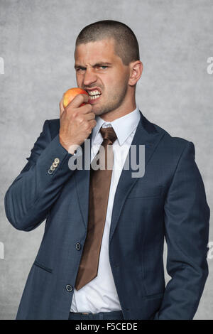 Ritratto di un giovane imprenditore bello mangiare mela rossa Foto Stock