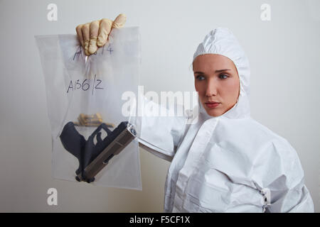 Femmina scienziato forense tenendo le armi e munizioni Foto Stock