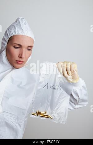 Femmina scienziato forense tenendo le munizioni come elemento di prova Foto Stock