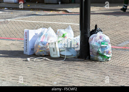 Bin di sacchetti e rifiuti sinistra sul mio un palo sul marciapiede, London, Regno Unito Foto Stock