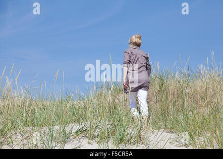 Un Senior passeggiate nelle dune su una spiaggia e godersi la pace e la tranquillità Foto Stock