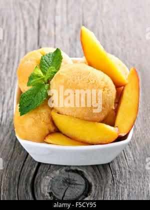 Peach gelato con la menta e fette in vaso su sfondo di legno Foto Stock