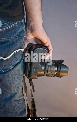 Un maschio di mano che tiene una grande fotocamera Foto Stock