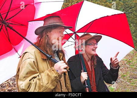 Due persone azienda red ombrelloni in una tempesta di pioggia in Eugene, Oregon Foto Stock