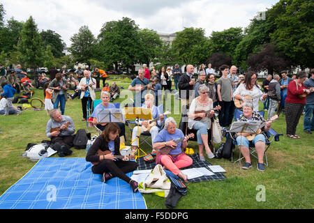 Le persone che giocano ukuleles presso la grande busk, parte dell'ukulele festival della Gran Bretagna a Cheltenham, Gloucestershire, Regno Unito Foto Stock