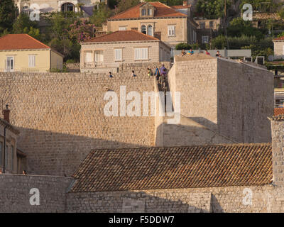 Dettaglio delle mura di fortificazione intorno alla città vecchia, Stari Grad, di Dubrovnik Croazia, turisti sightseeing, bassa luce del sole dorato Foto Stock