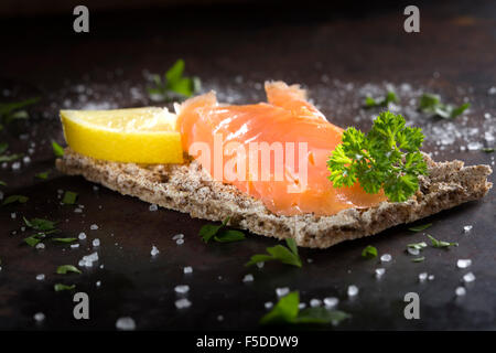 Salmone affumicato su cracker integrale con il prezzemolo, limone e sale Foto Stock