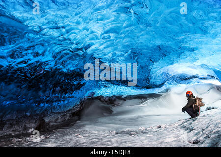 L'uomo traveler godendo landmark esotici, seduti nella caverna di ghiaccio, Skaftafell ghiacciaio Vatnajokull National Park, natura straordinaria Foto Stock