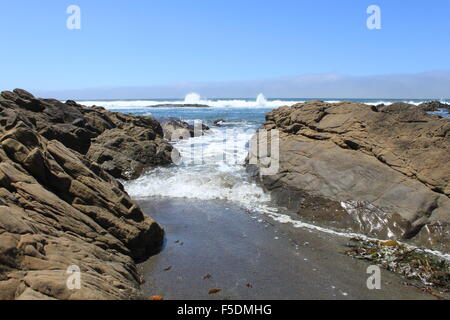 Le onde in arrivo tra le rocce . Onde che si infrangono sugli scogli creando un tuffo nel retro terreno . Tre di tre Foto Stock