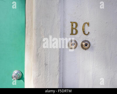 Close-up di due campanelli di porte su un stucco bianco parete mediante una porta verde con masaneta, Santa Barbara, California, Stati Uniti d'America. Foto Stock