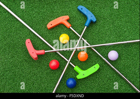 Un assortimento di golf in miniatura putters e palle di traverso sul campo in erba sintetica Foto Stock