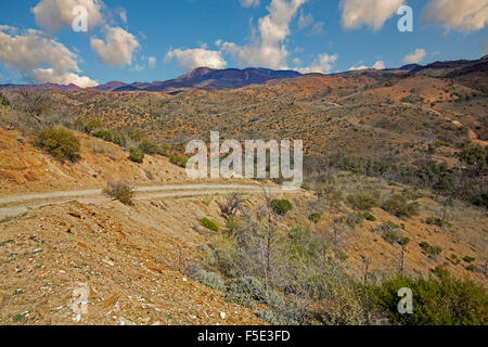 Lunga strada tortuosa serpeggiando in arido paesaggio collinare di Gammon gamme Parco Nazionale sotto il cielo blu in outback Australia del Sud Foto Stock