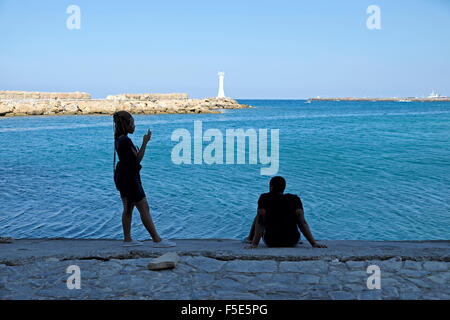 Persone turisti seduti lungo la banchina all'ingresso vicino al porto di Kyrenia a Cipro Nord KATHY DEWITT Foto Stock