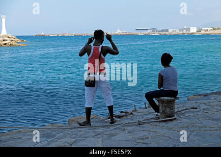 In Africa la gente giovane turista seduto guardando il mare lungo la banchina all'entrata di Kyrenia porto di Cipro Nord KATHY DEWITT Foto Stock