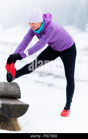 Sport e fitness ispirazione e motivazione. Giovane donna felice cross country in esecuzione in montagna sulla neve, giornata invernale di esercizio. Foto Stock