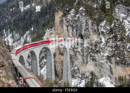 Bernina Express passa sul viadotto Landwasser, UNESCO e boschi innevati, Filisur, Canton Grigioni (Grigioni), Svizzera Foto Stock