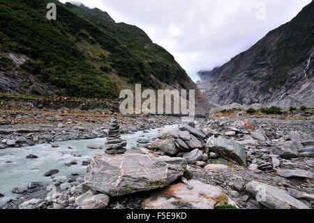 Due escursionisti sul sentiero accanto alle acque fluenti del fiume Waiho e una pista verso la 'Toe' del Ghiacciaio Franz Josef, Isola del Sud, Nuova Zelanda Foto Stock