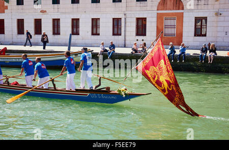 Un team di prendere parte alla Vogalonga, con la loro imbarcazione battente bandiera veneziano di un leone alato Venezia Veneto Italia Europa Foto Stock