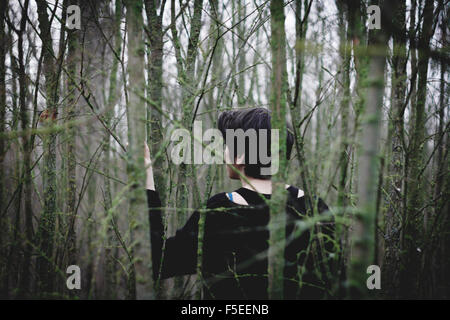 Vista posteriore di una donna perduta nella foresta Foto Stock