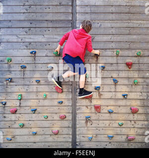 Ragazzo salendo sulla parete di arrampicata Foto Stock