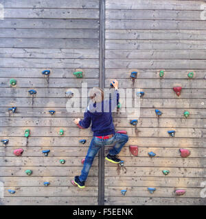 Ragazzo salendo sulla parete di arrampicata Foto Stock