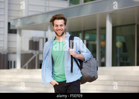 Ritratto di un allegro studente di college in piedi fuori con la schiena Foto Stock