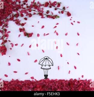 Donna concettuale che tiene un ombrello in piedi sotto una doccia fiorita Foto Stock