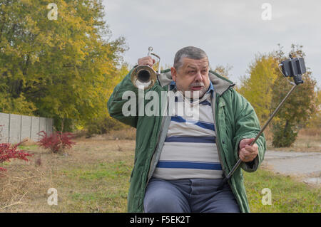 Funny Man senior rendendo volti mentre facendo selfie outdoor Foto Stock