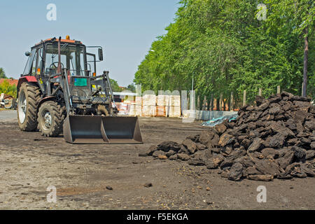 Un trattore che viene utilizzato per il caricamento del carbone nei camion per il trasporto. Foto Stock