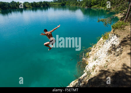 Giovane uomo salti della rupe per la pulizia, l'acqua turchese in Sulejow. La Polonia. Foto Stock