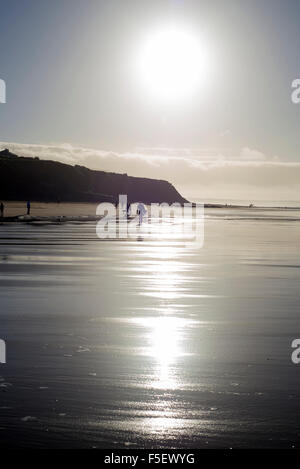 Silhouette di surfer e la gente fuori per una passeggiata mentre il sole tramonta a Ballybunion contea di Kerry Irlanda Foto Stock