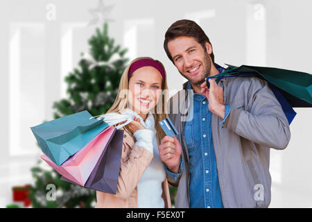 Immagine composita della coppia sorridente con borse per lo shopping nella parte anteriore della finestra Foto Stock