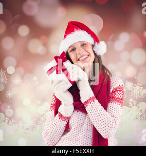 Immagine composita della donna attraente indossando santa hat con dono Foto Stock