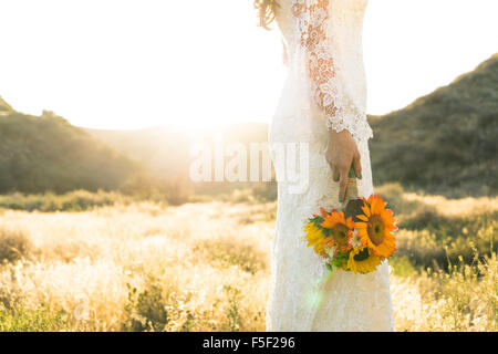 Una sposa mentre tiene il suo bouquet giù sul suo lato Foto Stock