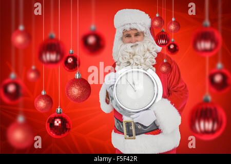 Immagine composita di felice santa tenendo un orologio Foto Stock