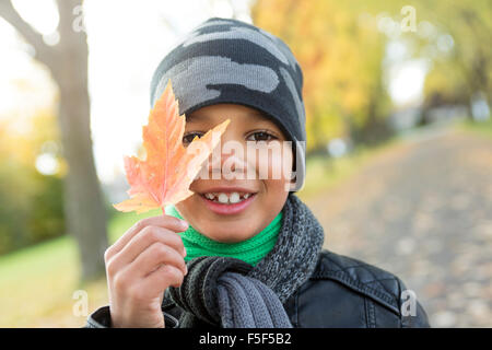 Ragazzo carino con foglie di autunno nel parco Foto Stock