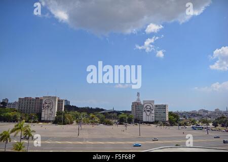 Rivolta verso immagini iconiche su edifici attraverso Piazza della Rivoluzione Cubana, palme ondeggianti e traffico, vista da Jose Marti statua Foto Stock