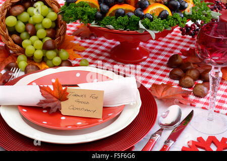 Rosso e bianco tema Ringraziamento tavolo con posto individuale impostazione, cibo e cornucopia, closeup su Grazie per la buona compagnia pl Foto Stock